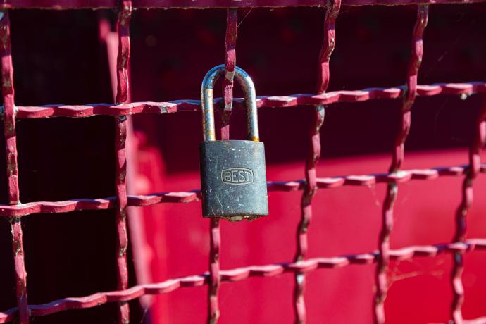 A lock hanging on a fence